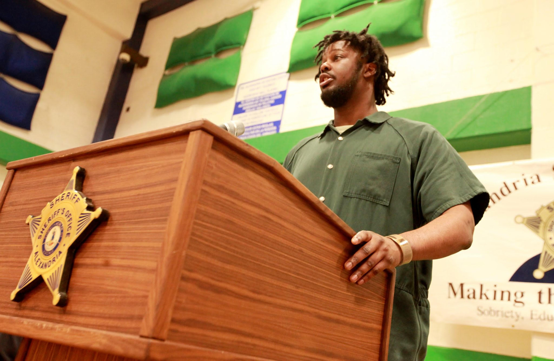 A participant in a correctional facility program reads his poem aloud from a wooden podium during a Heard writing event.