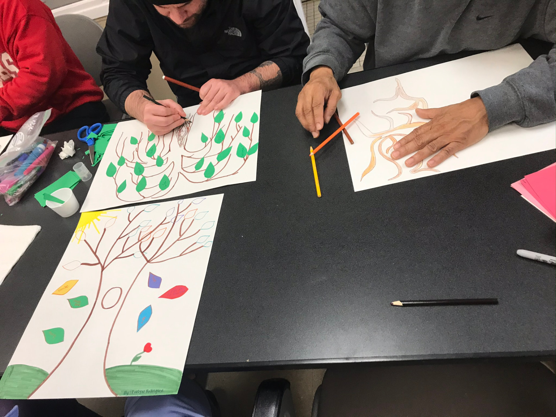 Participants seated around a table draw their own gratitude trees during a workshop.