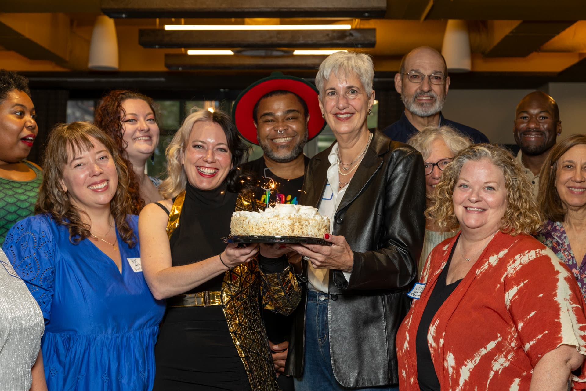 Heard staff, board members, and supporters gather around a celebration cake at a community event.