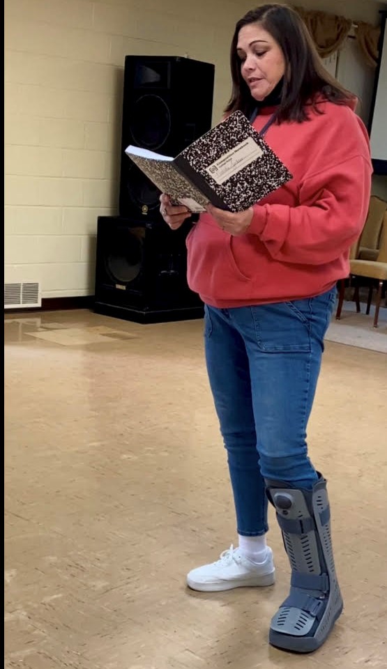 A participant reads her writing aloud from a composition notebook during a spoken word session.