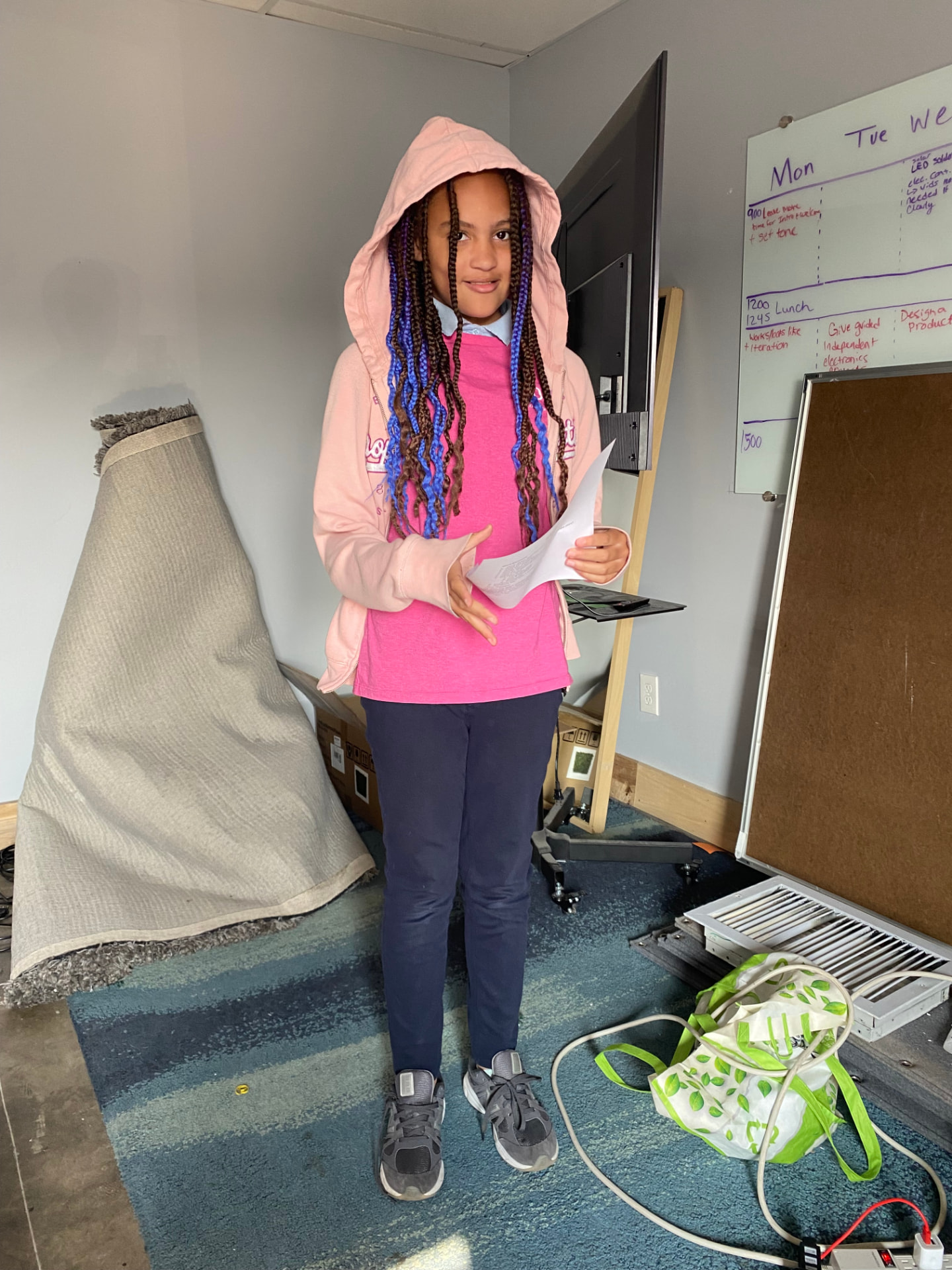 A young participant stands and presents from her notes during a public speaking workshop.