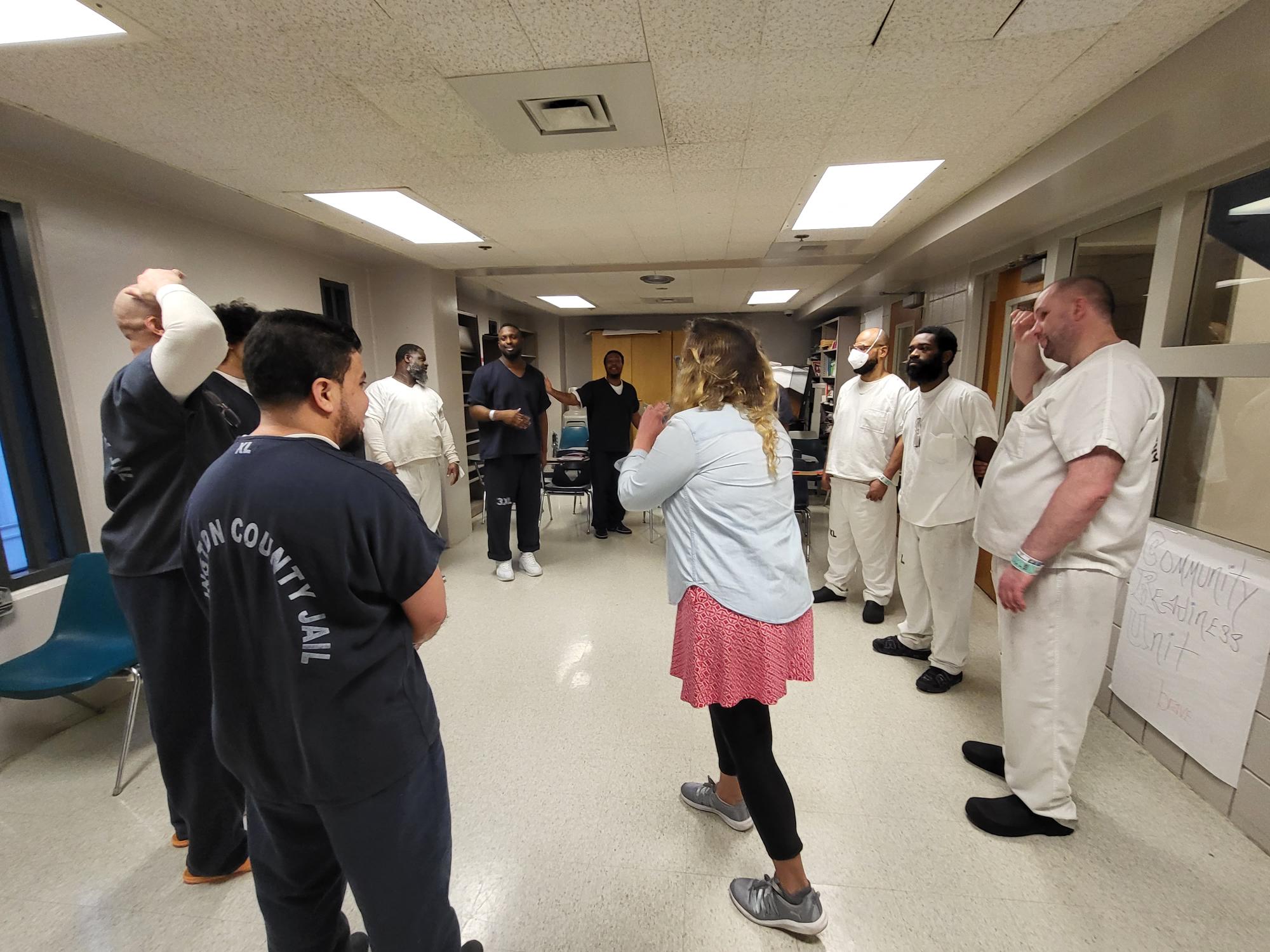 A teaching artist leads an improvisation exercise with participants at a detention facility.